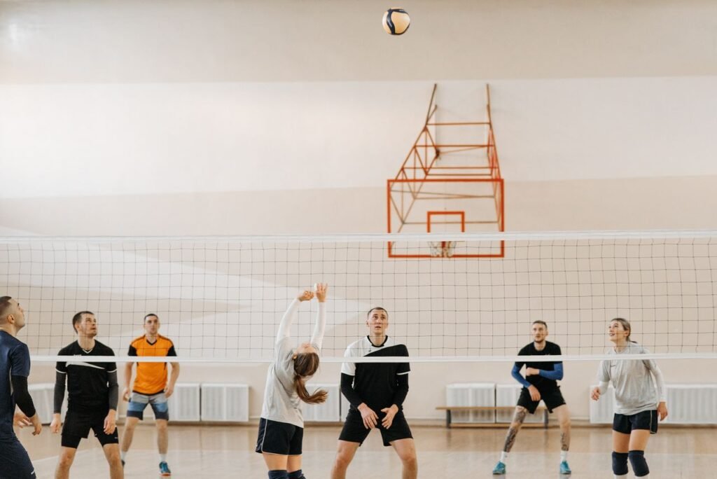 Adults playing an intense indoor volleyball game. Perfect depiction of sportsmanship and teamwork.